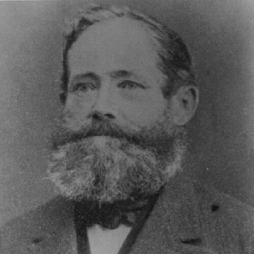 Das Bild zeigt ein historisches Schwarz-Weiß-Porträt von Wilhelm Eduard Schmeißer. Dargestellt ist ein Mann mit Vollbart und zurückgekämmtem Haar, der einen Anzug mit Weste und Fliege trägt.